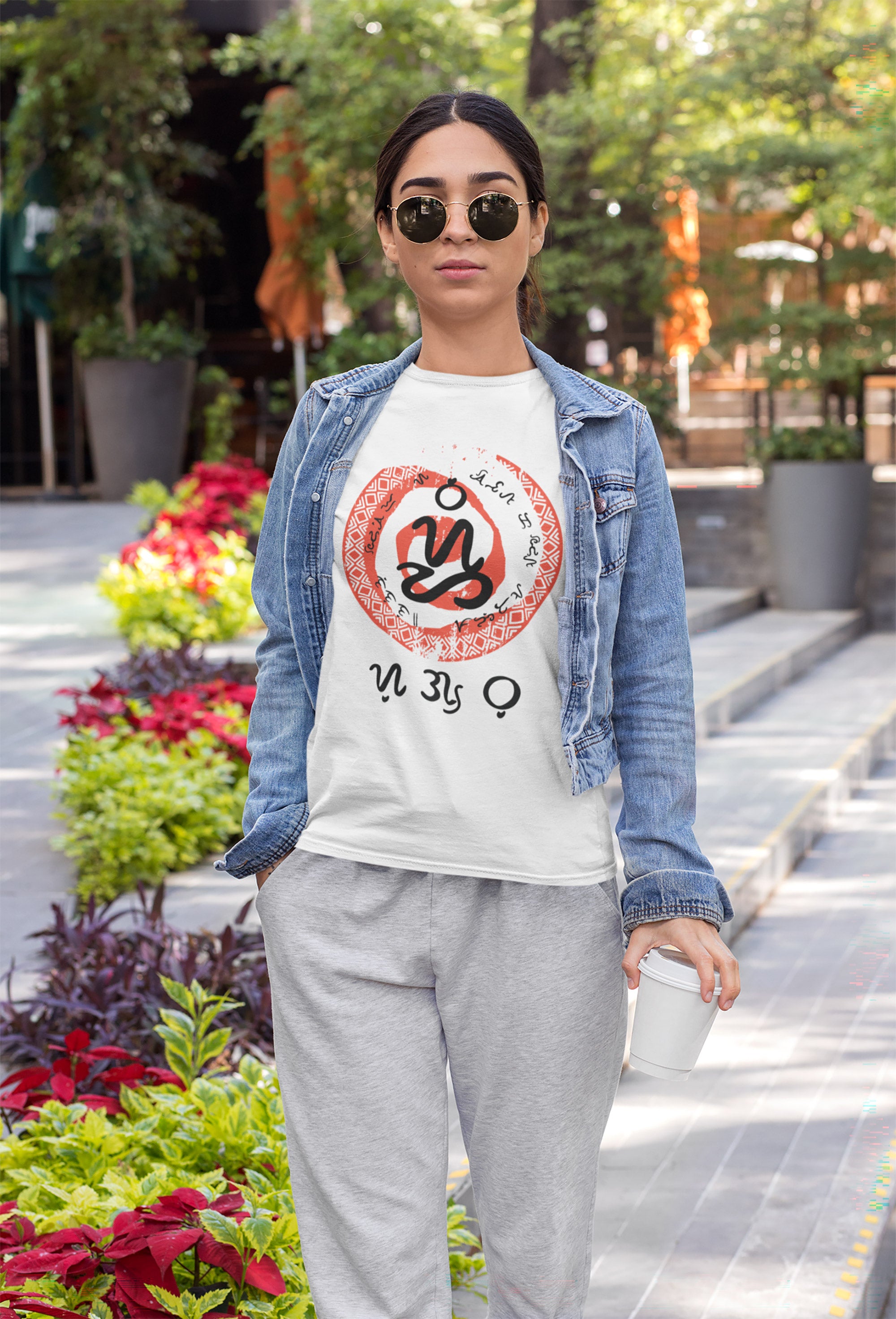 Filipina wearing a white t-shirt with a red and black badlit script design and the word sugbo in filipino script, standing outdoors with plants and a building in the background.