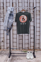 Green t-shirt with graphic design and the word Cebu in the filipino script badlit on a rack against a textured wall.