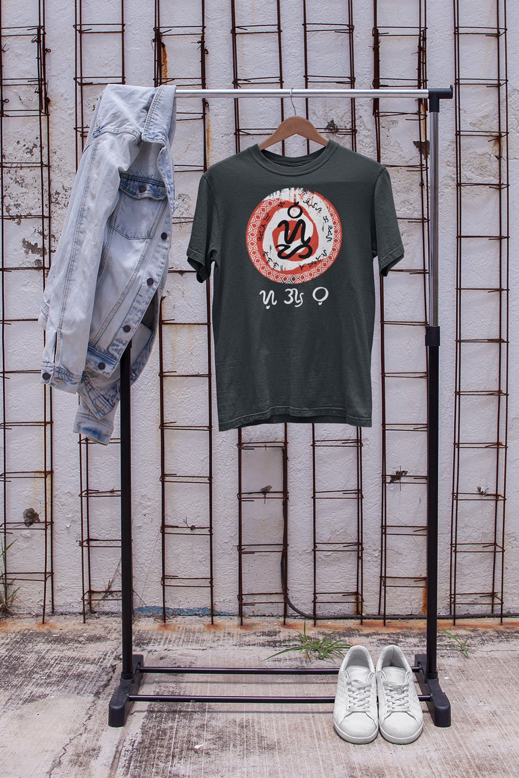 Green t-shirt with graphic design and the word Cebu in the filipino script badlit on a rack against a textured wall.