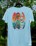 Ocean blue Filipino surf shirt with Badlit script on a hanger in a nature setting