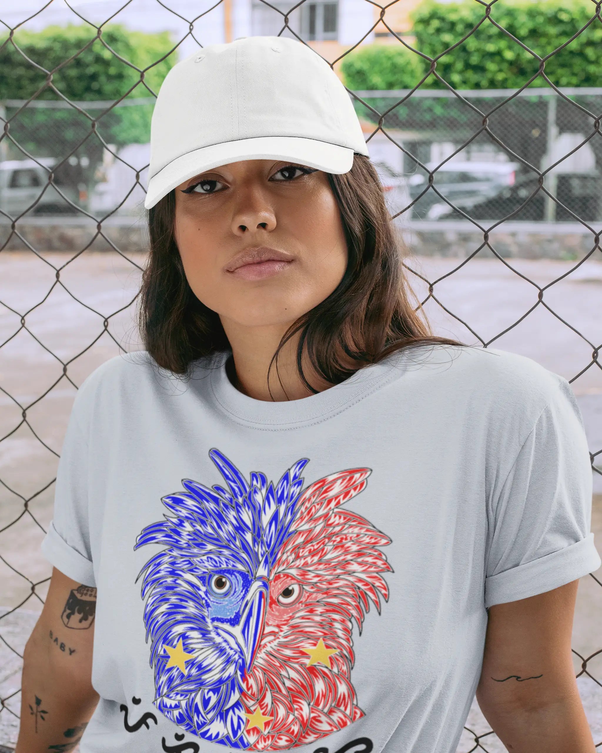 Woman in a light blue Philippine Eagle shirt with a dad hat by a chain link fence