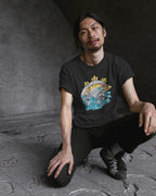 Black Pilipinas shirt with koi tribal art, worn by a man crouching on concrete steps.