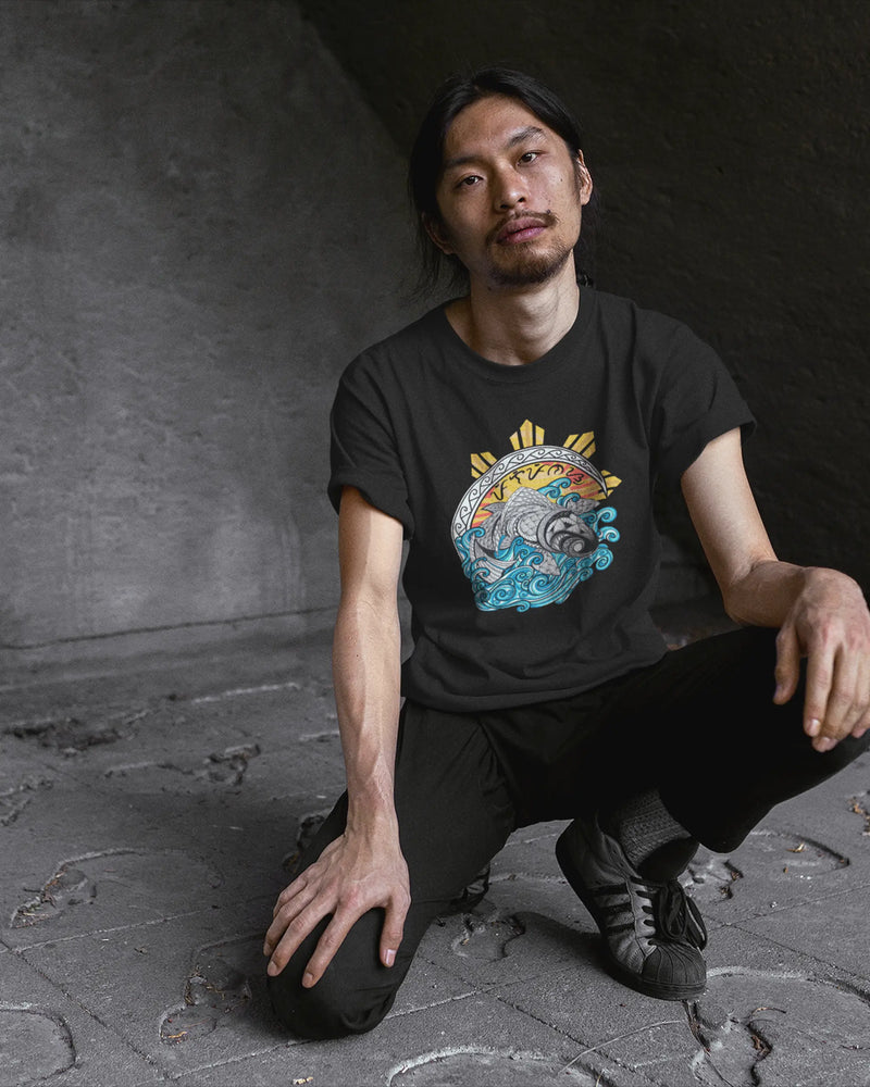 Black Pilipinas shirt with koi tribal art, worn by a man crouching on concrete steps.