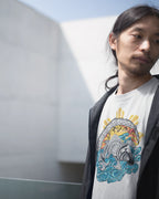 White filipino tribal art shirt with a koi and sun design, worn against a modern building.