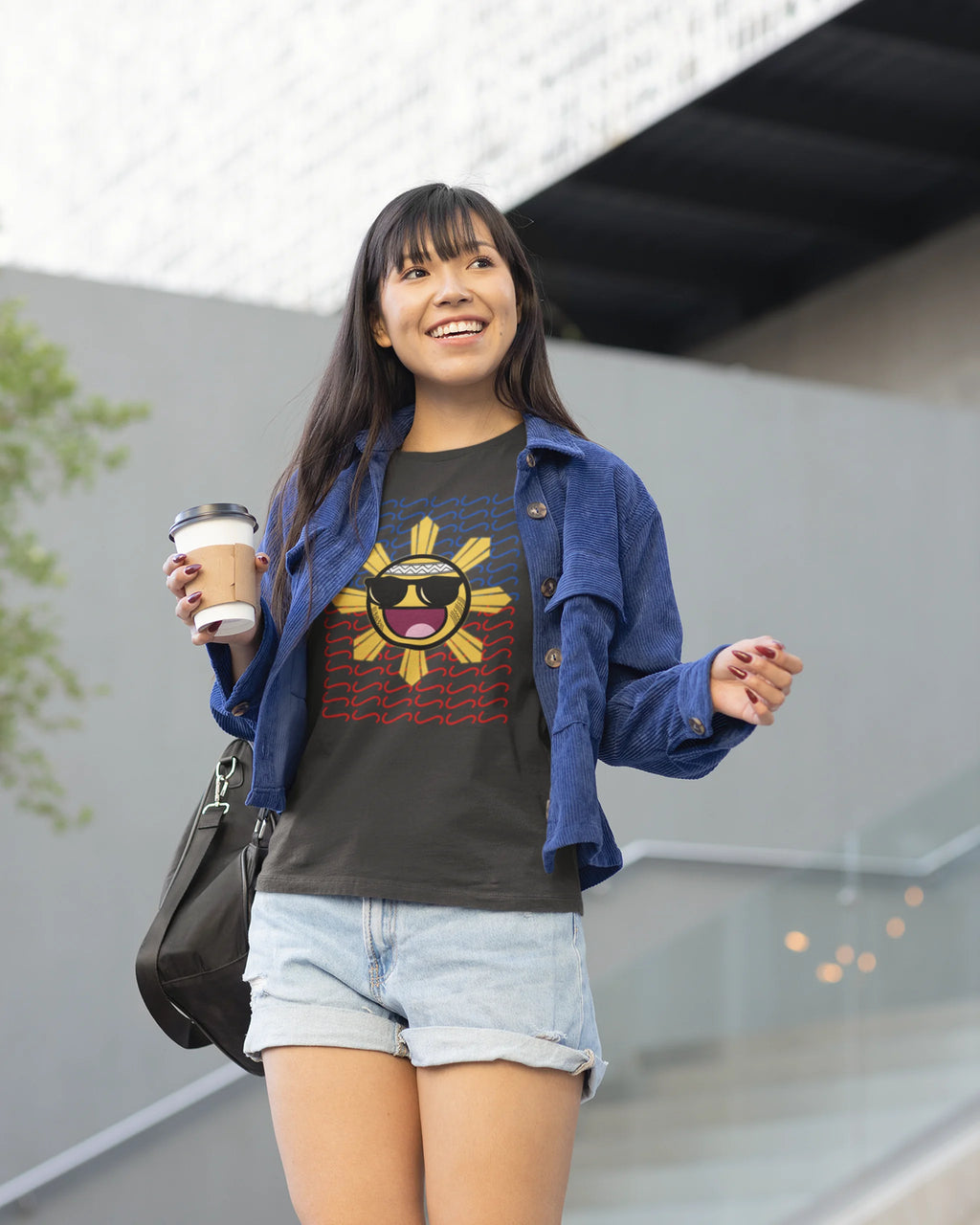 Woman holding a latte in a Baybayin t-shirt, casual filipino streetwear with a smiling sun graphic.