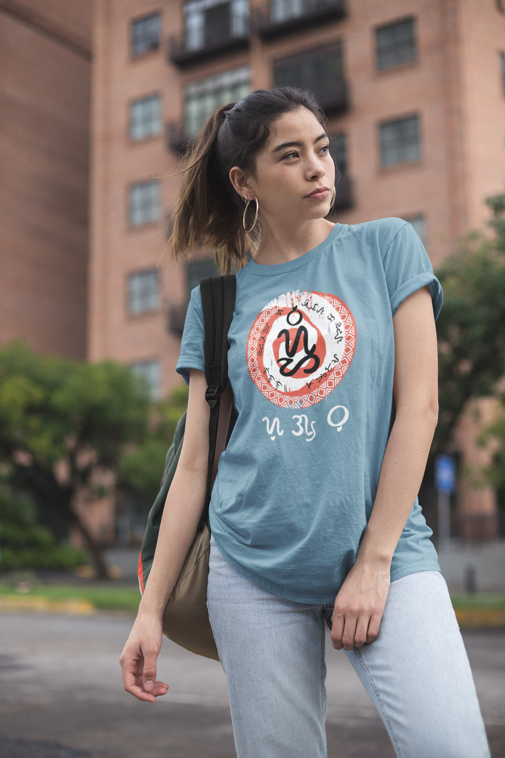 Woman wearing a blue unisex t-shirt with a graphic design showing the words Sugbo and Bisaya in pre-colonial Filipino script.