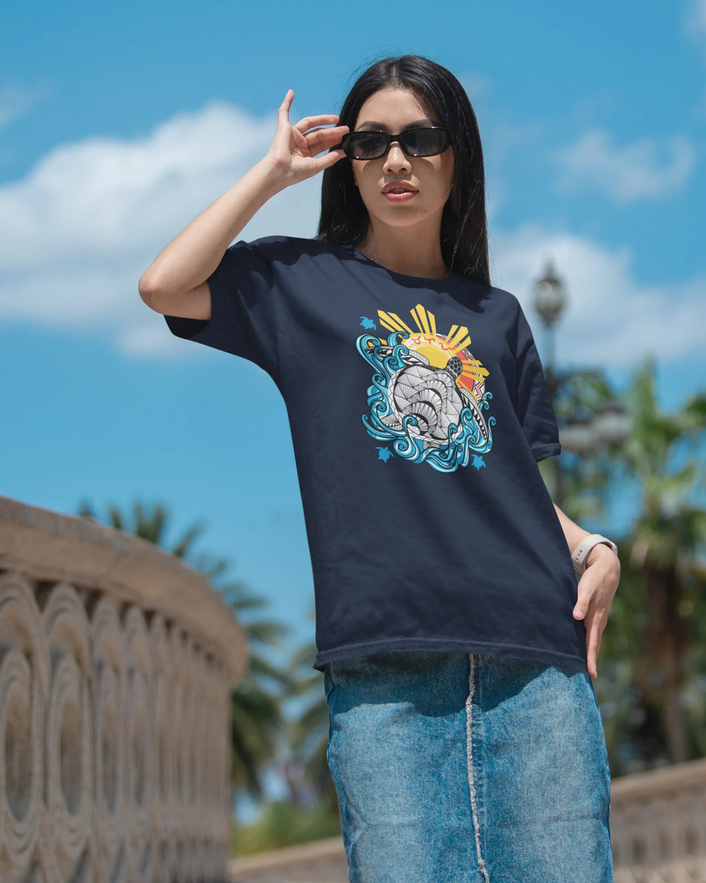 Baybayin Malaya Pawikan tee in navy – styled on a stone bridge with palm trees